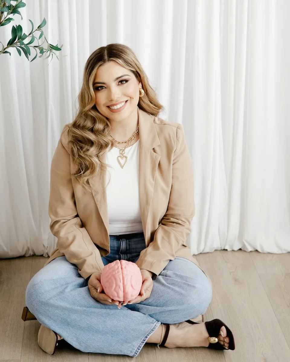 Melanie, sentada en el piso, sostiene un modelo de cerebro en las manos y sonríe