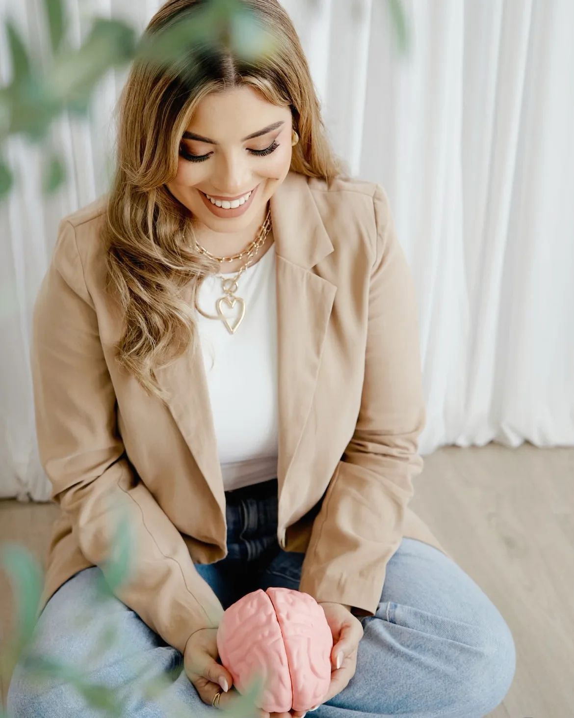 Melanie sonríe mirando hacia abajo, con las manos sobre un modelo de cerebro